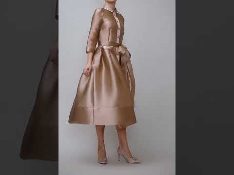 O rochie ca o oda elegantei si siluetei anilor '50 Este confectionata din organza de culoarea bej auriu si vine cu o jupa separata din jerse fin bej. Gulerul mic, nasturii in ton din fata, buzunarele (da!), fusta voluminoasa si cordonul lung din talie – toate aceste detalii o transforma intr-un model castigator: clasic si atemporal